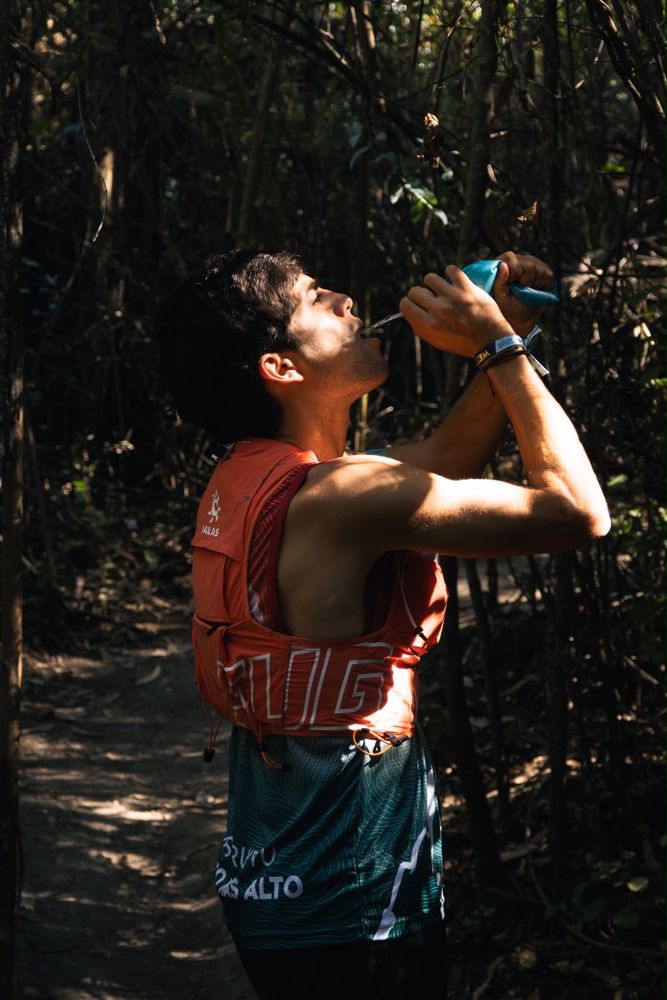 Corredor tomando ZENIT de su soft flask en el sendero
