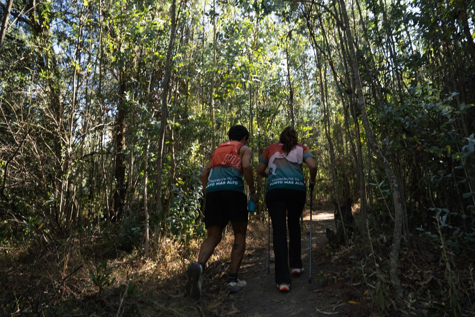 Dos corredores subiendo por un bosque con camisetas ZENIT